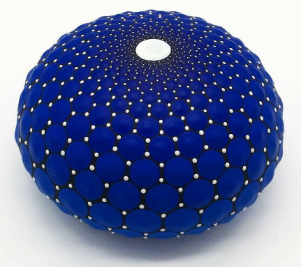 Blue mandala art 
painted on stone, showcasing intricate dot patterns and a central white dot, 
embodying mesmerizing beauty.