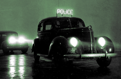 two old cars at night, the one 
in front with a 