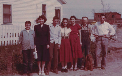 a line of folks at 
a Kansas farm: 2 boys, 2 young women, a young man, an 
older couple and an Irish Setter named Teddy